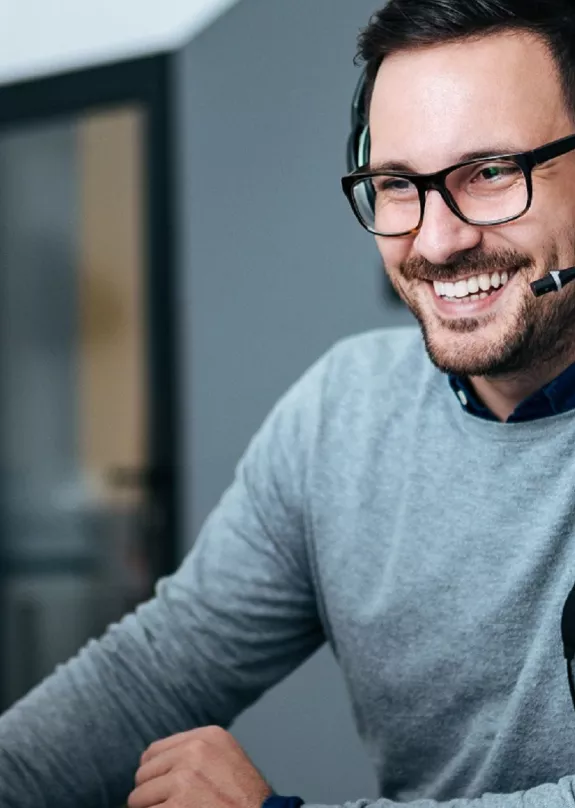 A man using a computer whilst wearing a headset