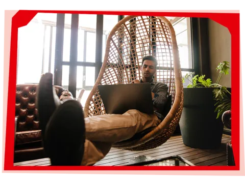 Man using laptop in hammock chair
